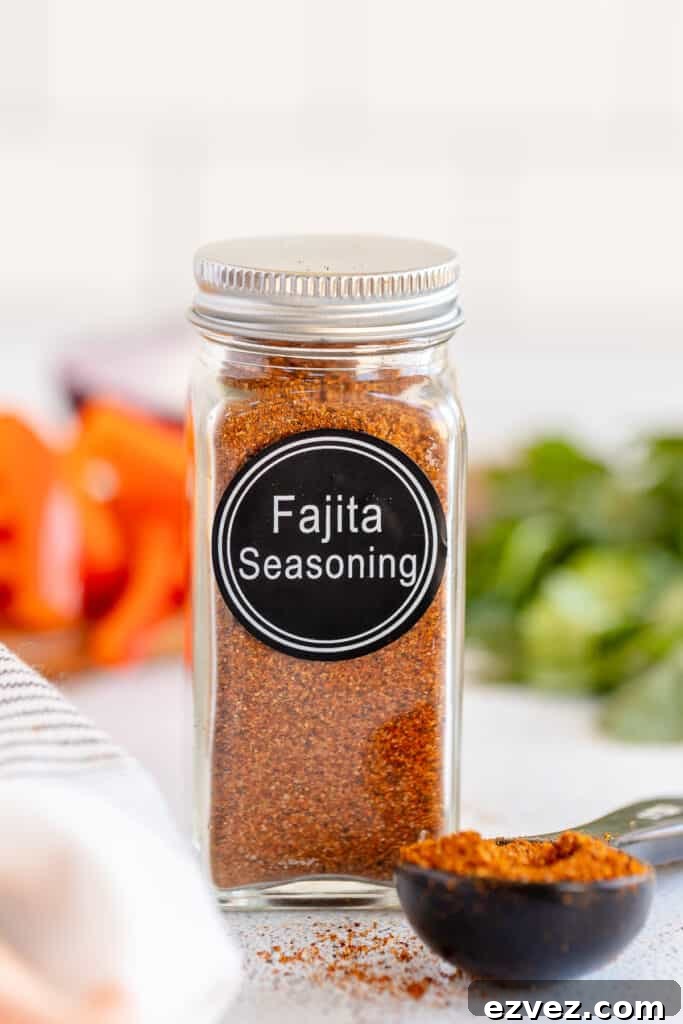 Homemade Fajita Seasoning Blend for Authentic Mexican Flavor 7 A spice bottle with a label that reads Fajita Seasoning and filled with brown spice next to a measuring spoon full of the spice.