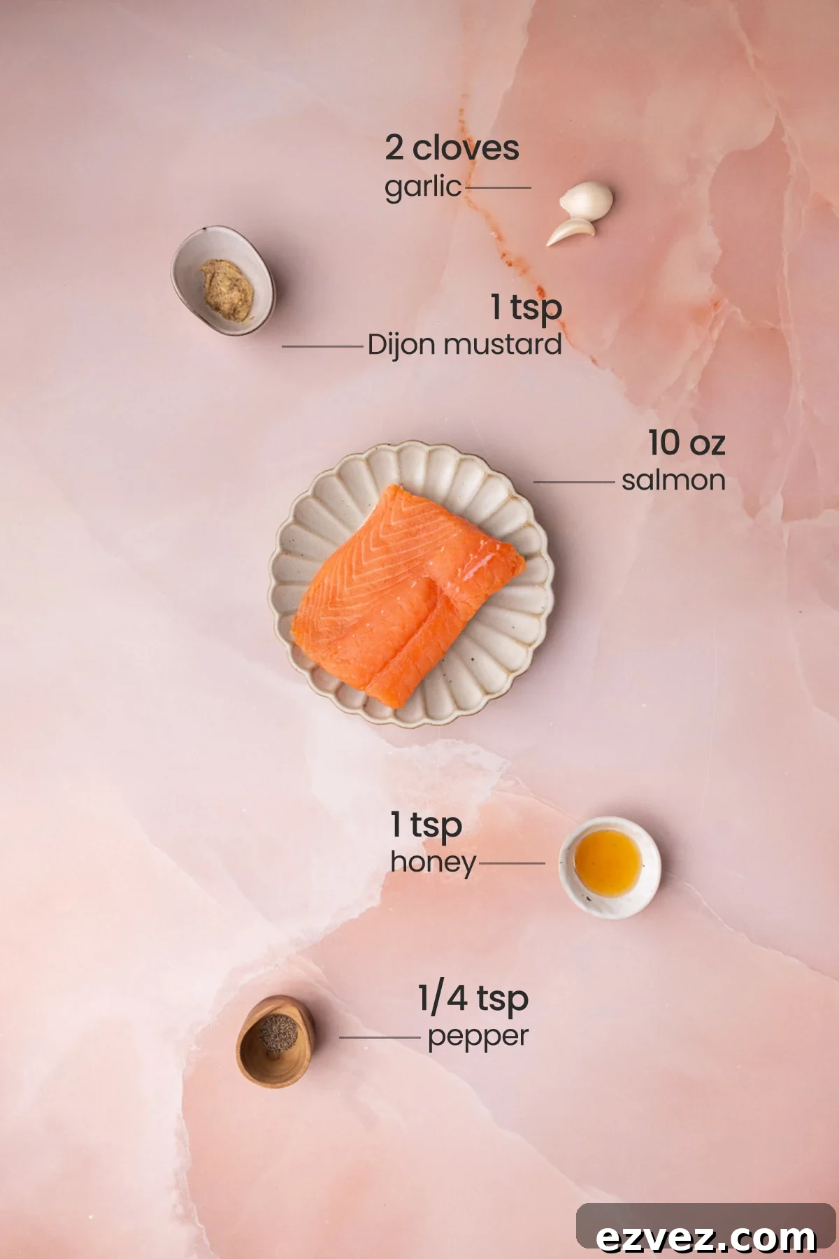 Overhead view of all ingredients for honey mustard salmon - garlic, Dijon mustard, salmon, honey, and pepper.