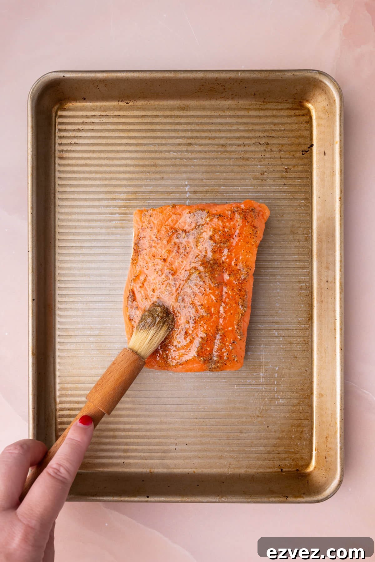 Brushing raw salmon with honey mustard marinade.