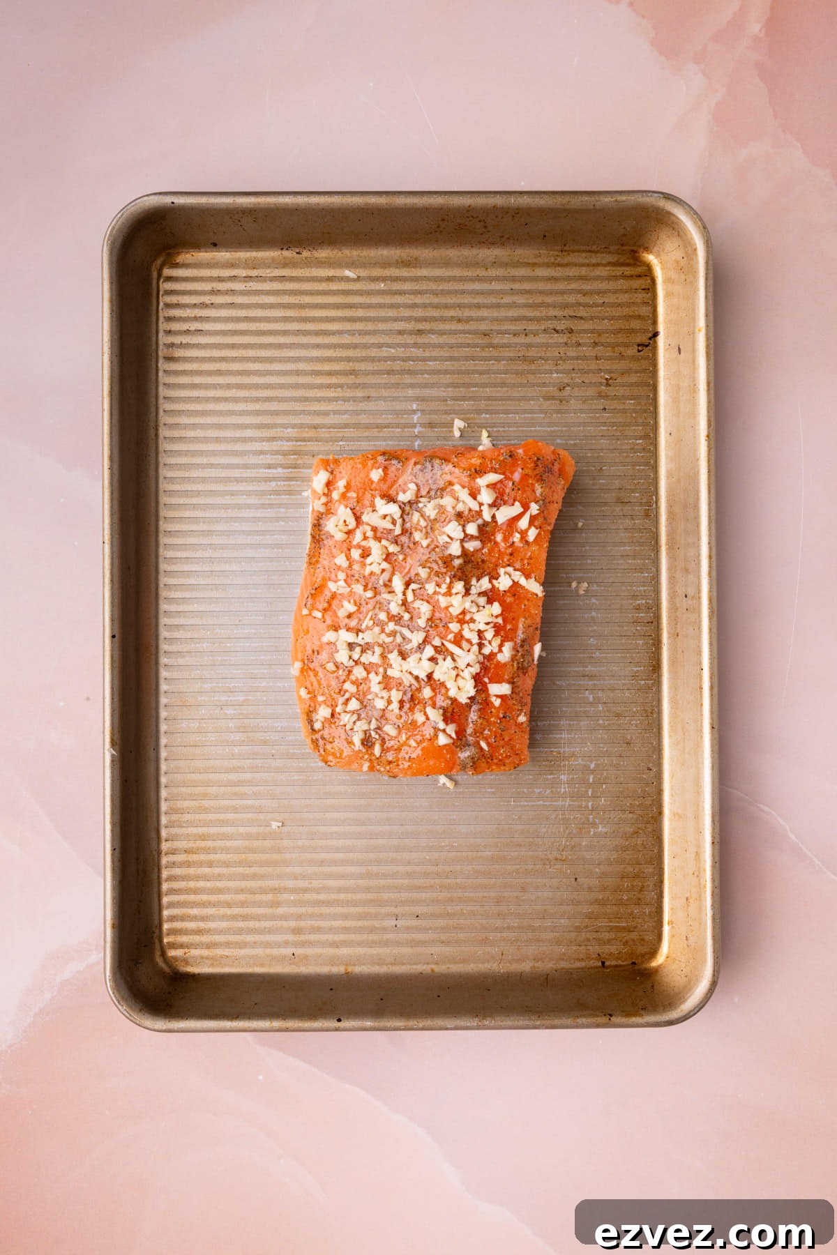 Minced garlic on top of honey mustard salmon prepped and ready for the oven.