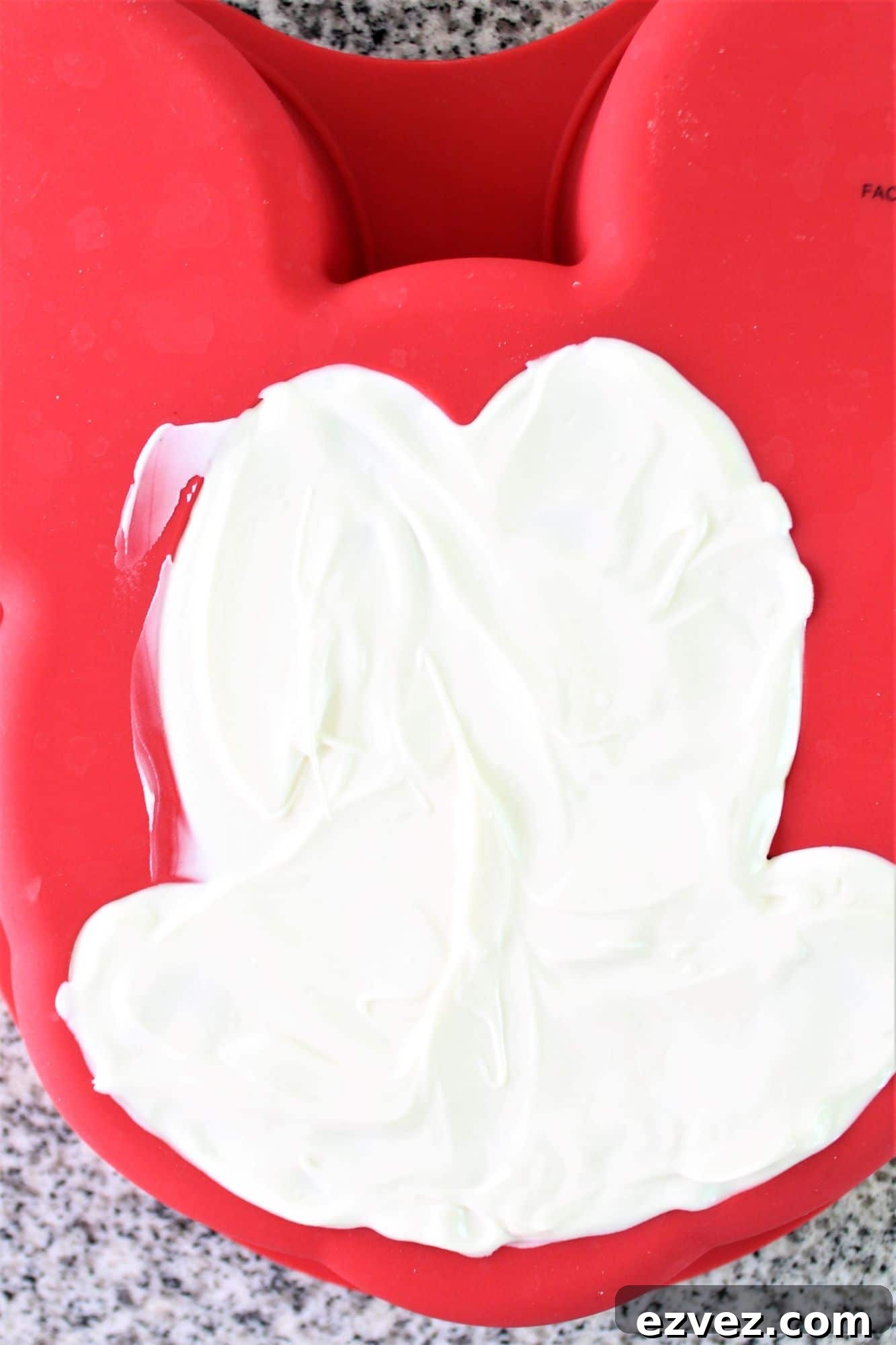 Decadent Gluten-Free Chocolate Cake Recipe for Perfect Texture 15 white chocolate spread onto mickey face of red silicone cake mold.