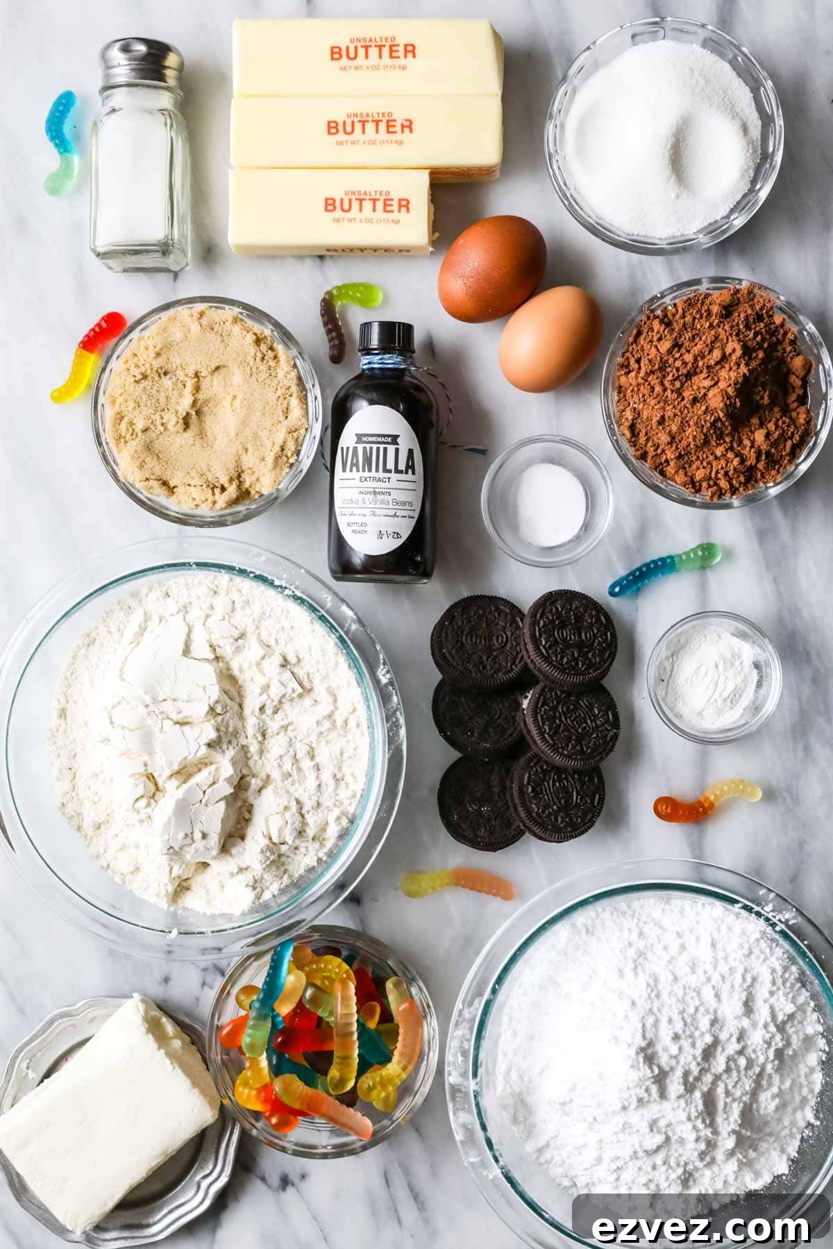 Overhead view of ingredients including cocoa powder, gummy worms, Oreos, and more.