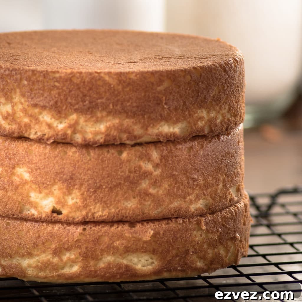 Golden cake layers stacked on a cooling rack three layers high.