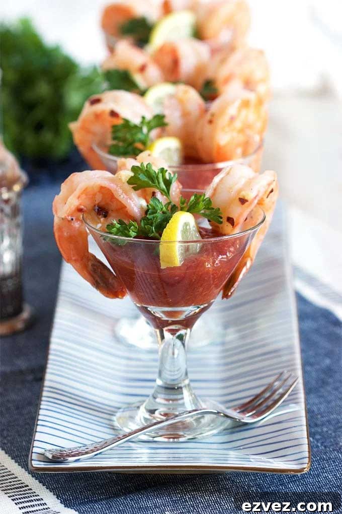 Shrimp presented in individual glasses, aligned in a row on a blue-striped rectangular platter.
