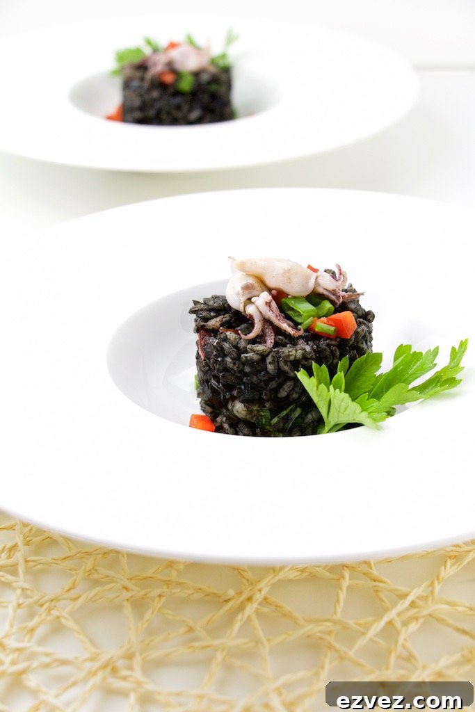 One risotto presented in fancy white bowl, garnished with parsley and whole squids, with second in background.