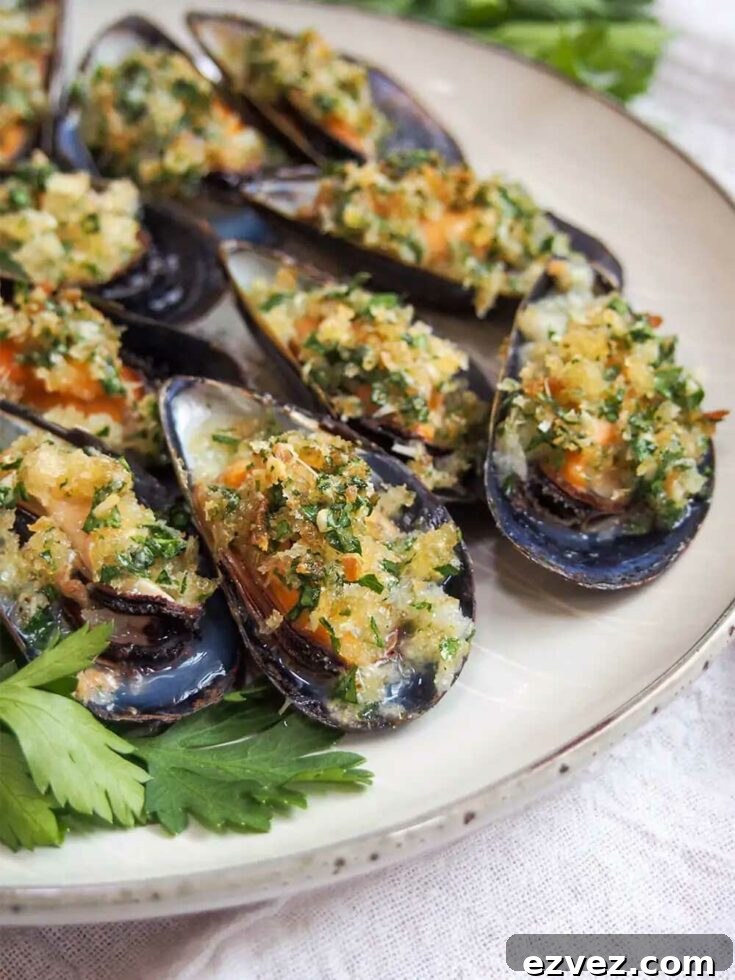 Closeup of mussels on cream-colored serving plate garnished with parsley sprigs.