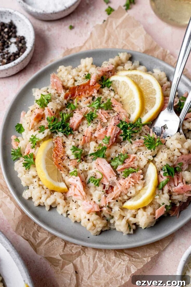 Risotto on gray plate with forks, garnished with lemon and parsley and surrounded by little dishes of extra seasonings.