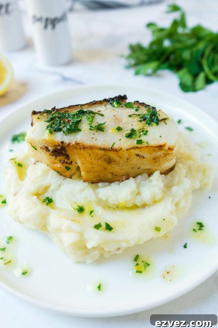 Fish plated for Thanksgiving dinner atop mashed potatoes on white plate.