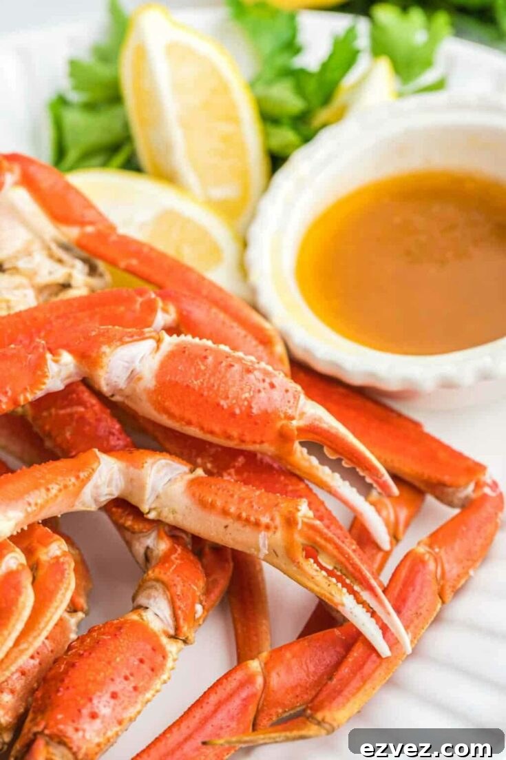 Closeup of crab legs on white platter with lemon wedges and dish of melted butter dip.