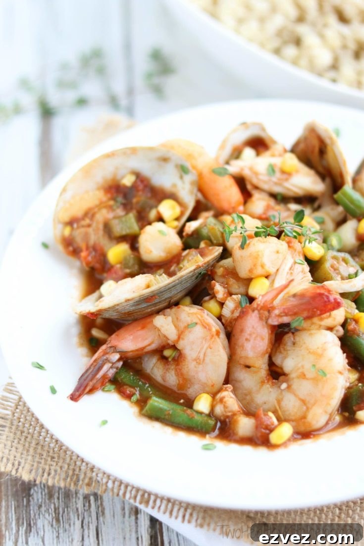 Side closeup of stew in a white-rimmed bowl so you can really see the individual shrimp, clams and other seafood.