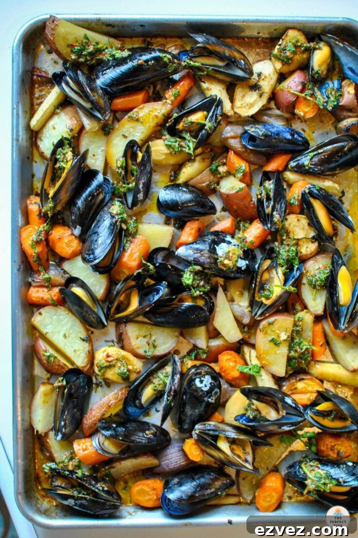 Overhead of baked seafood and veggies still on baking tray.