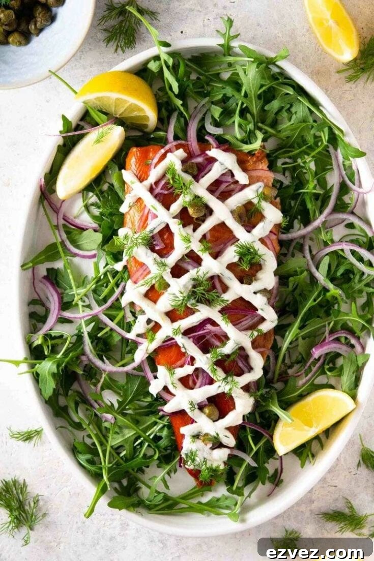 Overhead of trout recipe presented on oval platter with various garnishes strewn nearby.