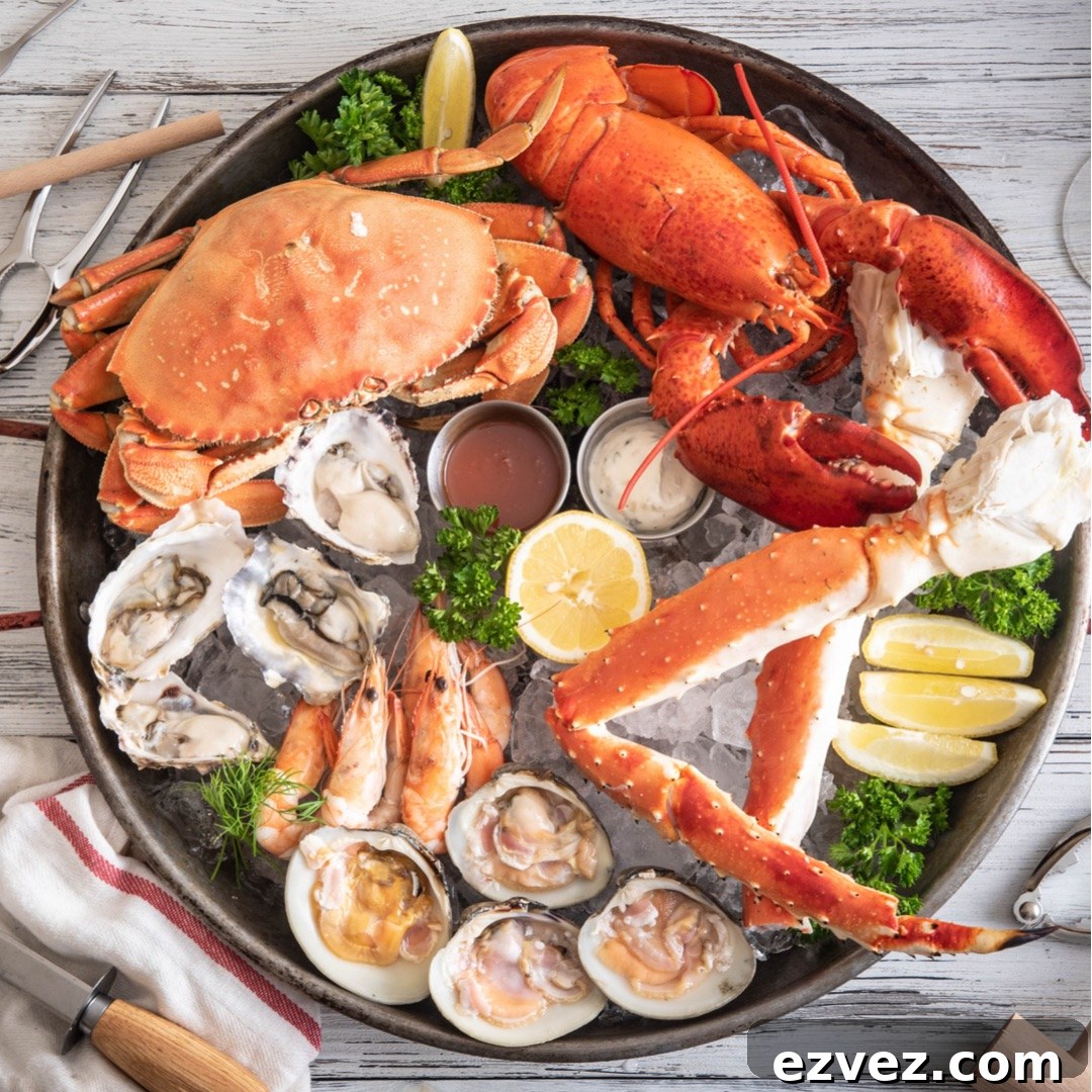 Overhead of Thanksgiving seafood assortment atop ice in a round metal platter, with crab crackers and other implements alongside.