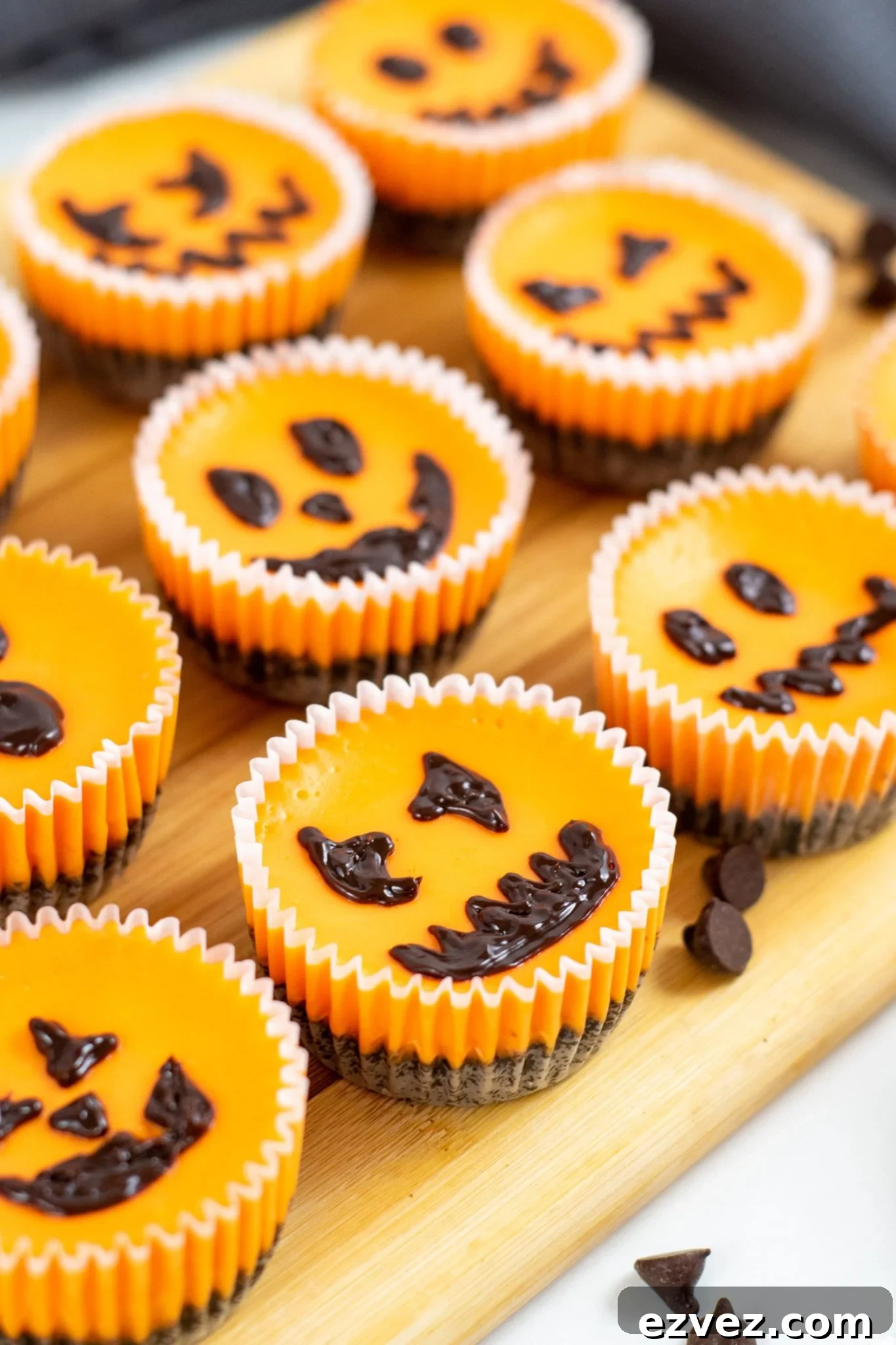 Jack-o'-Lantern Halloween Cheesecake Recipe for Party Treats 3 Cutting board filled with mini Halloween cheesecakes with all different faces.
