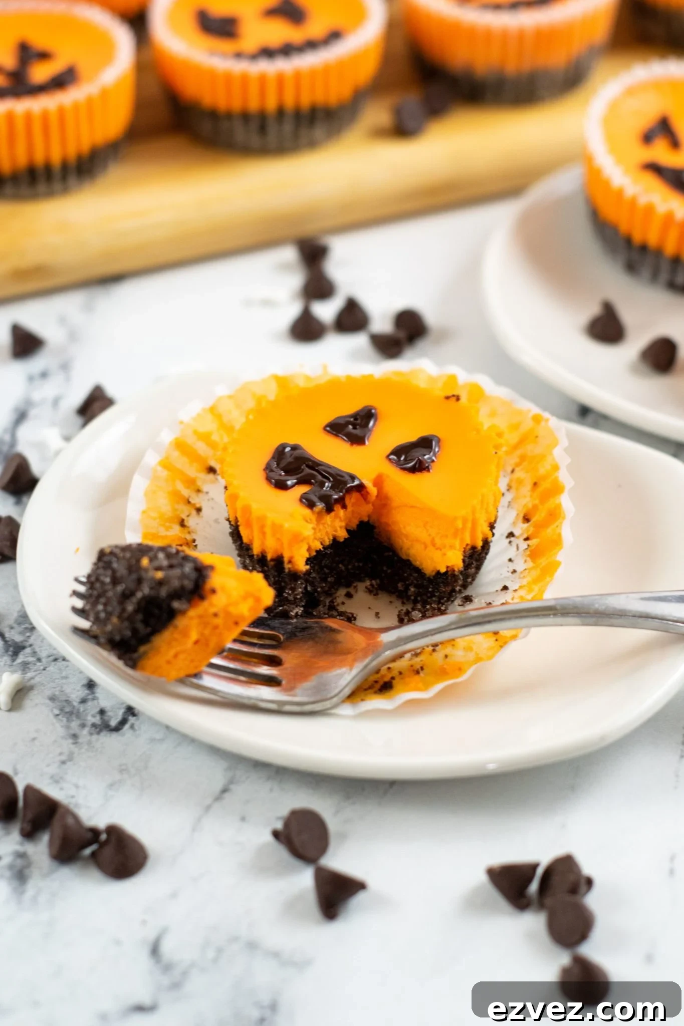 Jack-o'-Lantern Halloween Cheesecake Recipe for Party Treats 8 A white dish with a mini Halloween cheesecake on the plate with a fork full on the side.