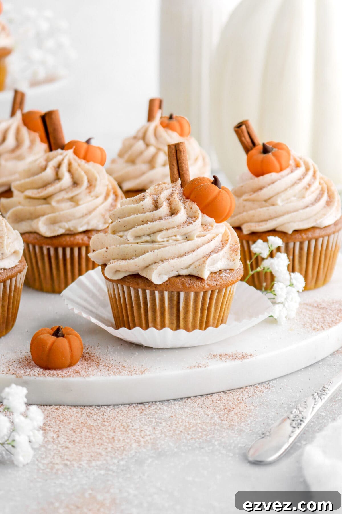 Pumpkin Caramel Poke Cake Recipe — Gooey Fall Dessert 12 frosted pumpkin cupcakes on marble surface.