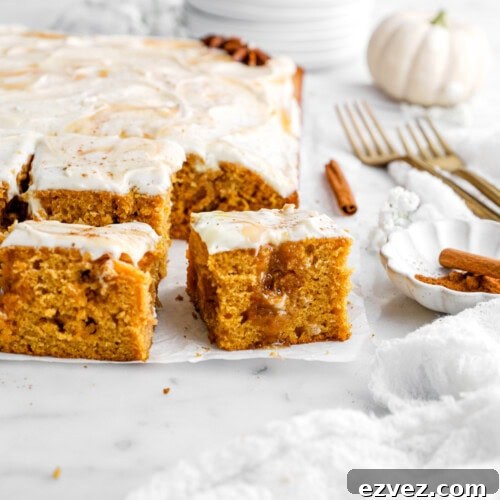 Pumpkin Caramel Poke Cake Recipe — Gooey Fall Dessert 13 pumpkin poke cake on parchment paper with cinnamon sticks, gold forks, and pumpkins around.