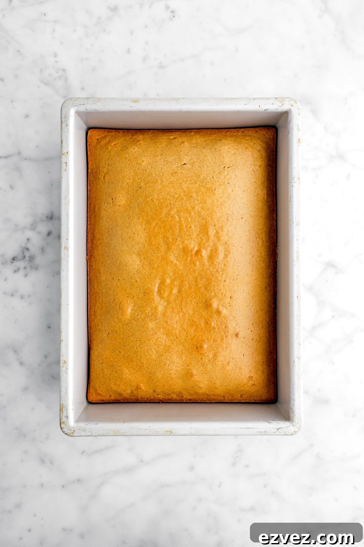 Pumpkin Caramel Poke Cake Recipe — Gooey Fall Dessert 5 baked pumpkin cake in cake pan.