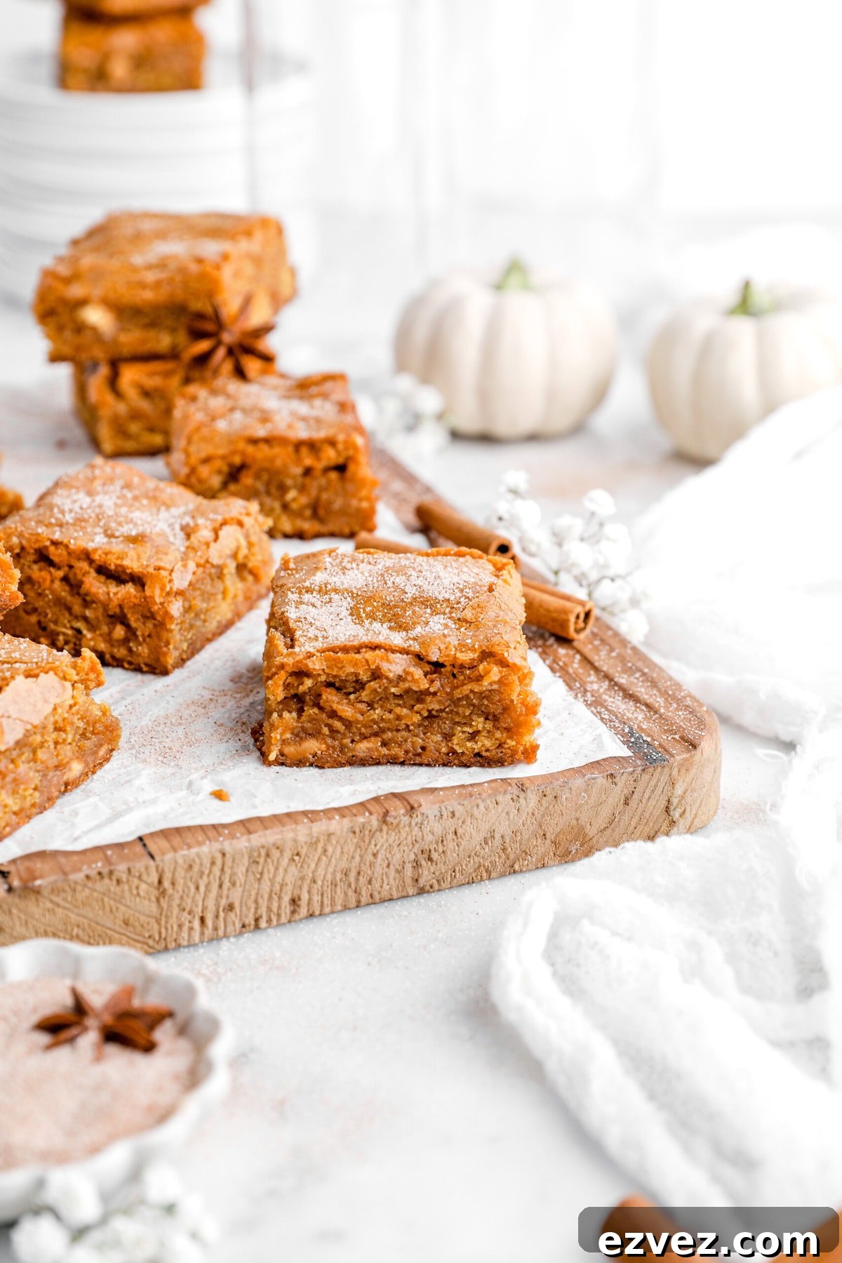 Pumpkin Caramel Poke Cake Recipe — Gooey Fall Dessert 10 pumpkin blondies on parchment lined wood serving board.