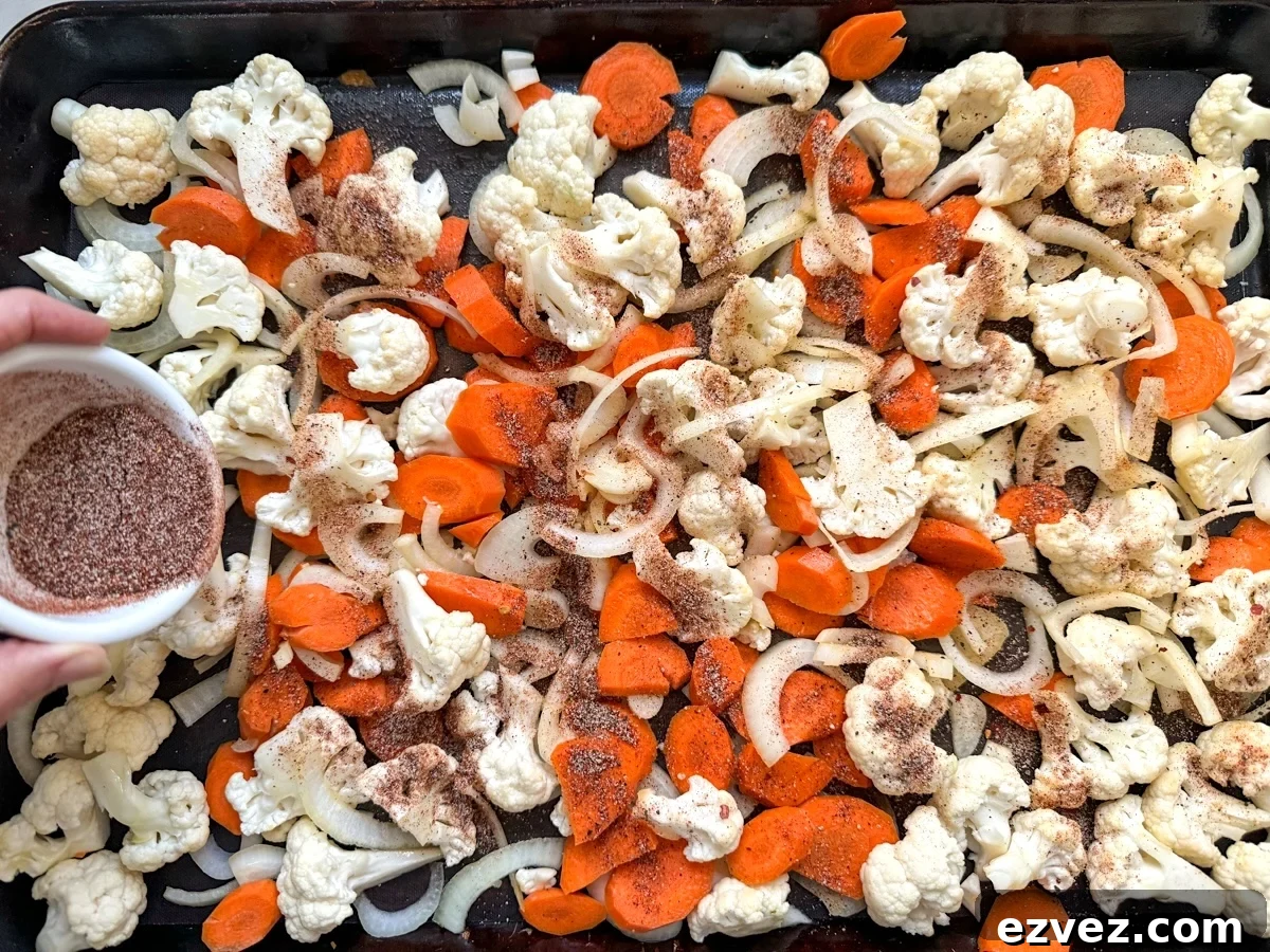 seasoning cauliflower and carrots on sheet pan