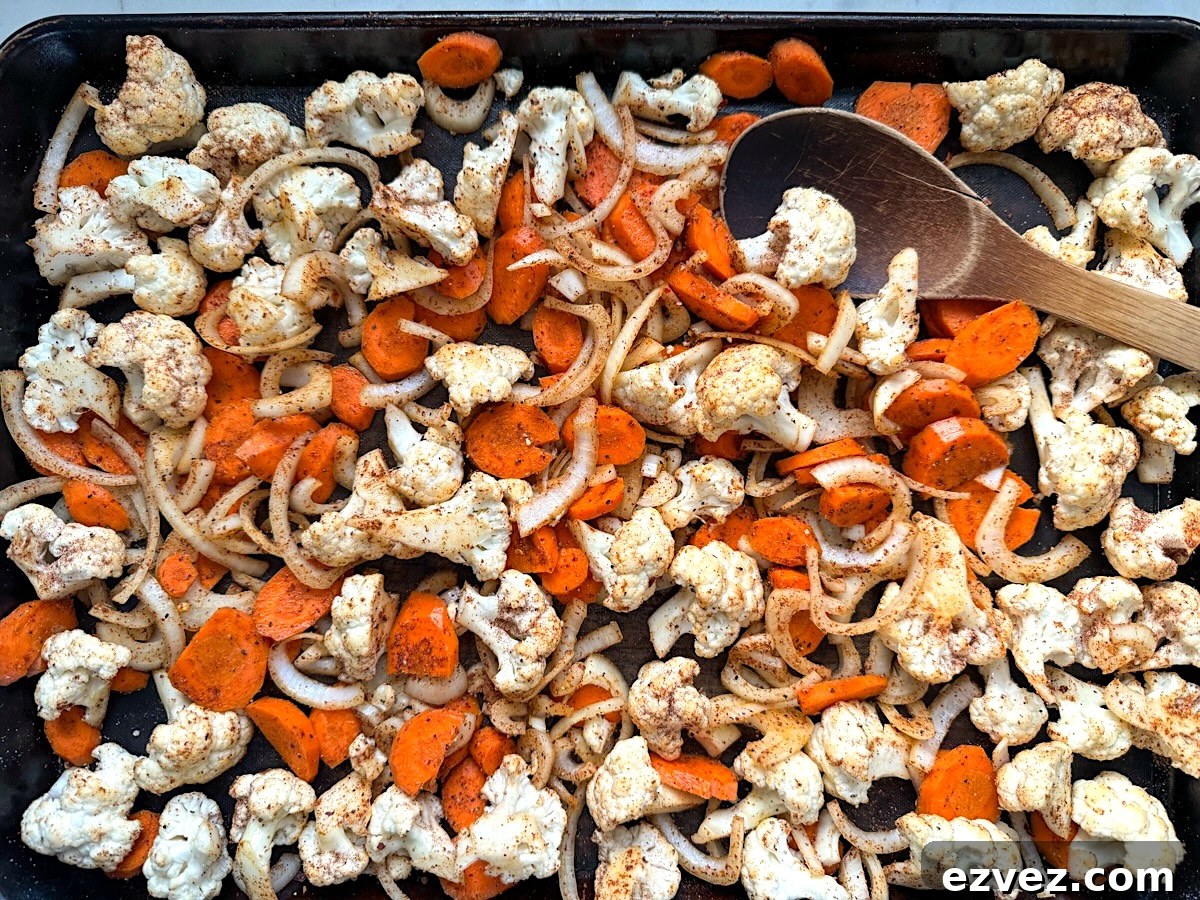 mixing vegetables on baking sheet with wood spoon