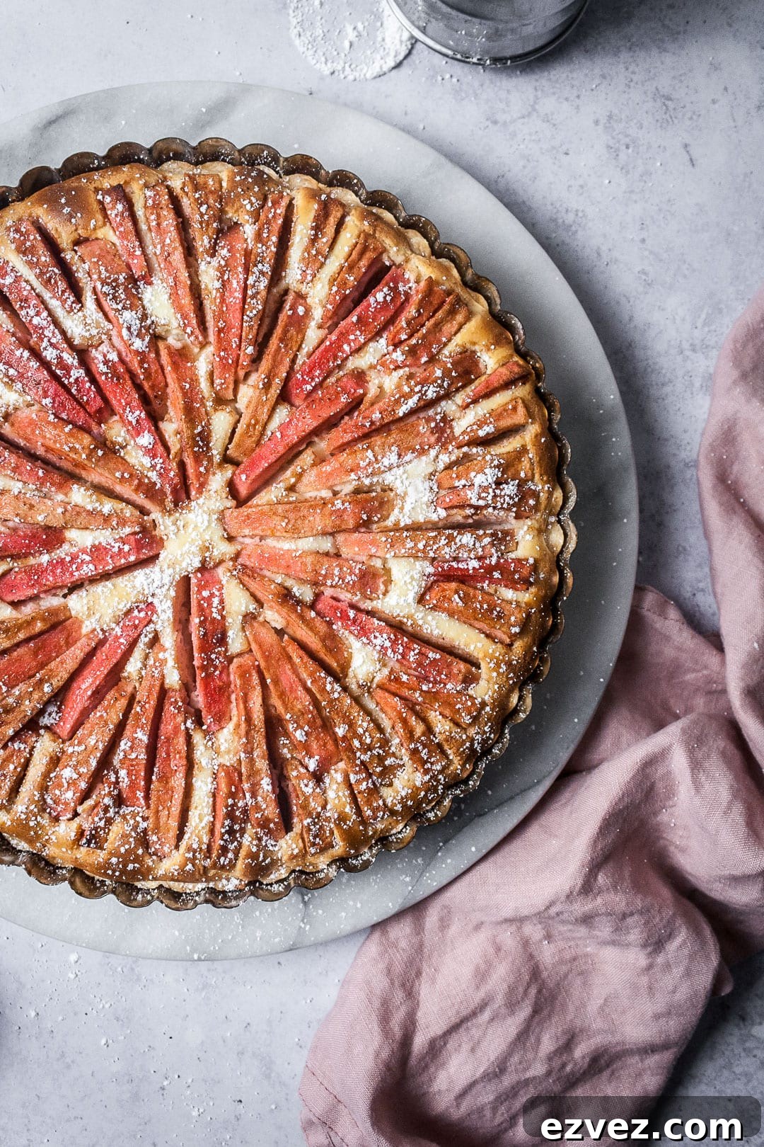 Pink Apple Tart with Cream Cheese Filling on a marble platter with a grey background