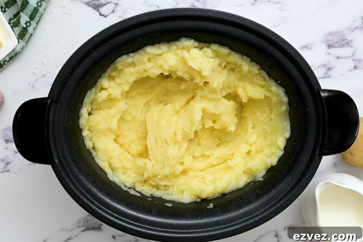 Crockpot filled with mashed potatoes after slow cooking.