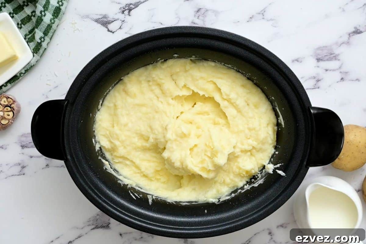 Mashed potatoes in crockpot after adding milk and sour cream.