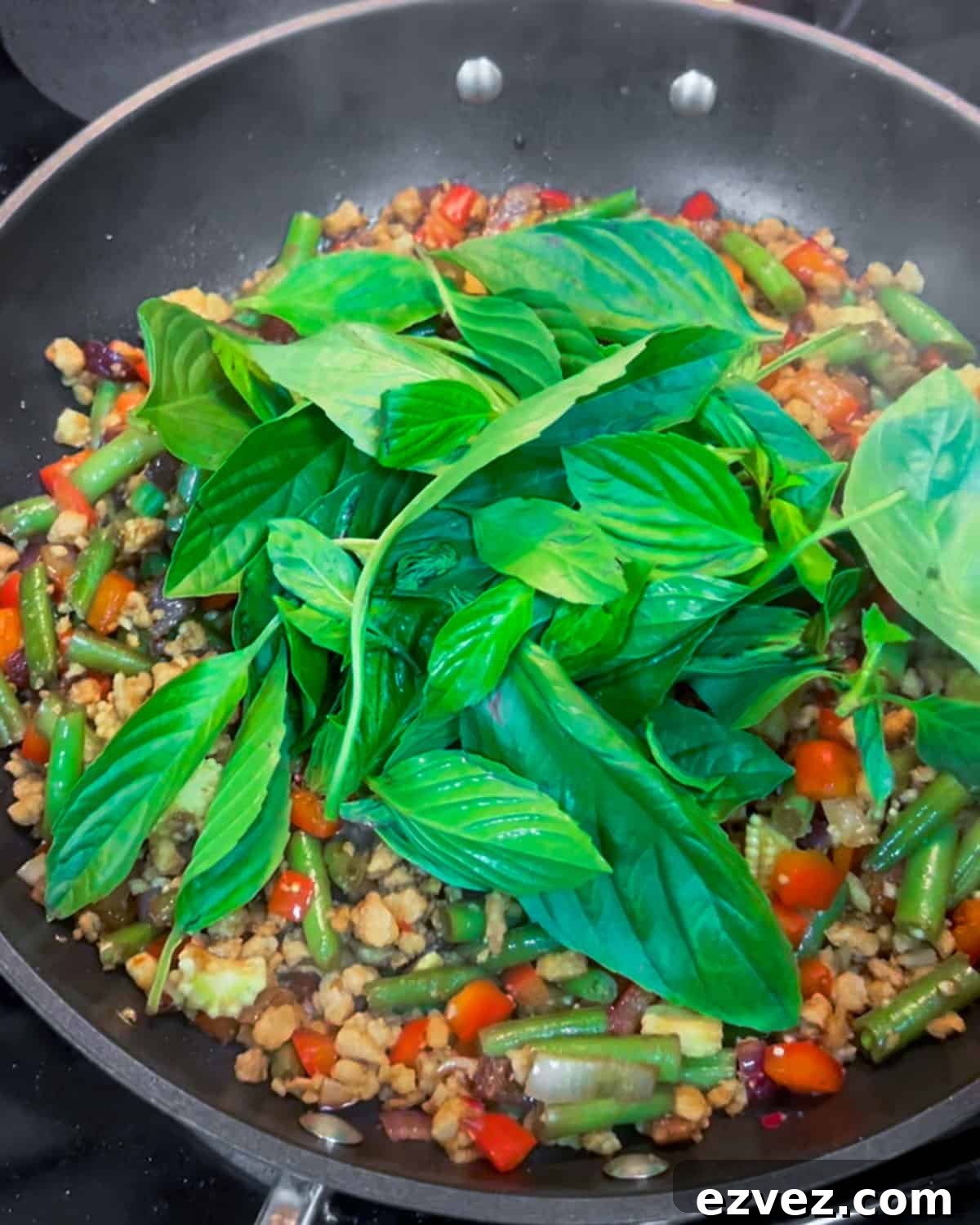 Photo of thai basil leaves being added to the stir fry.