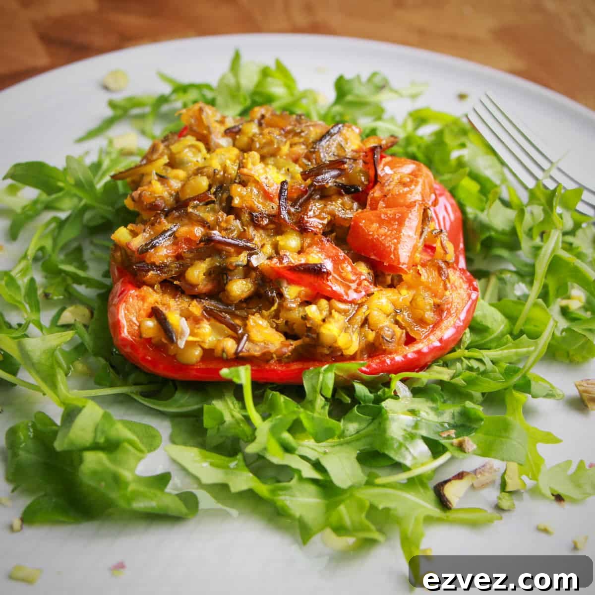Photo of a red pepper stuffed with spiced mung beans and wild rice, on a bed of rocket.