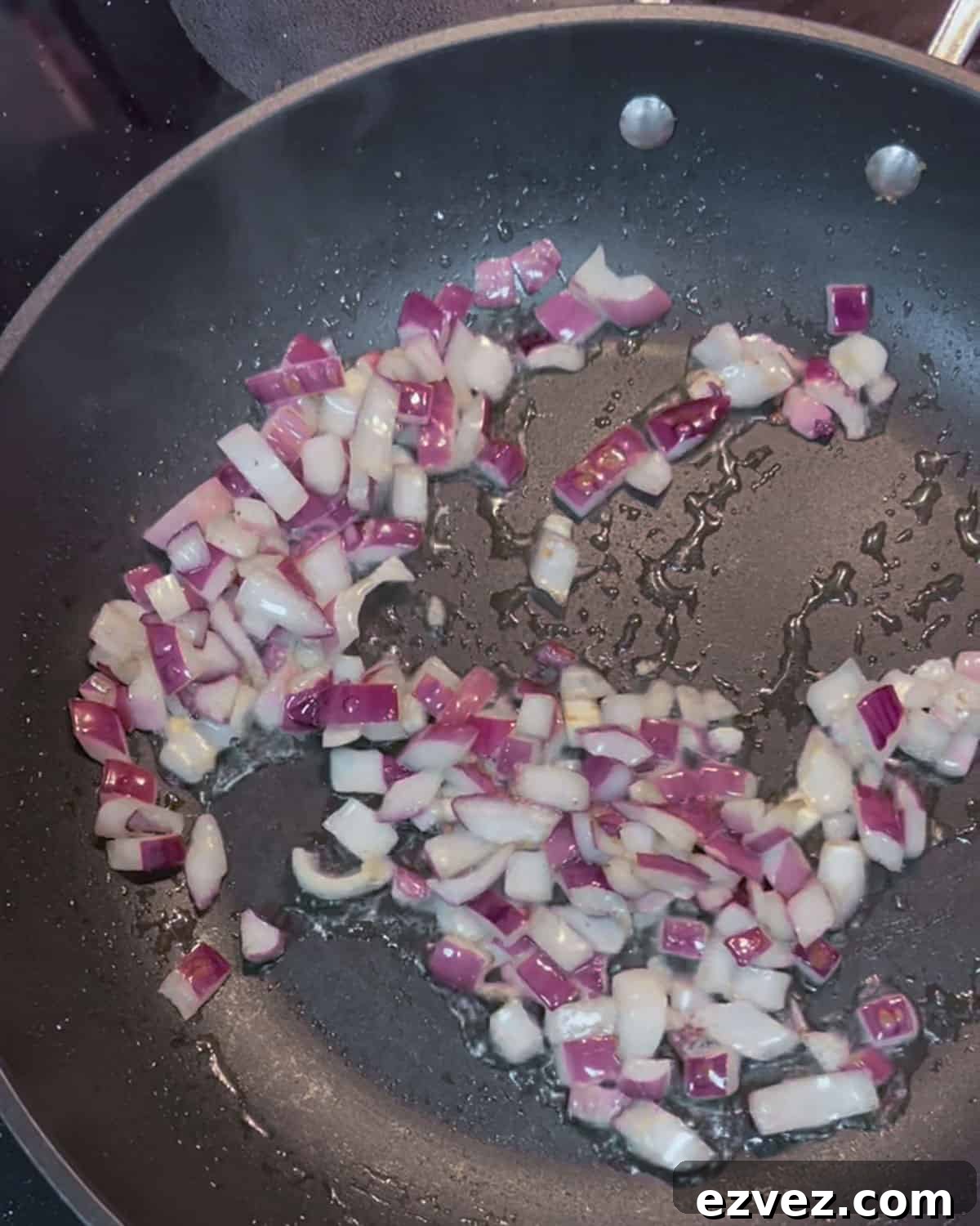 Photo of stir-frying red onion in a pan.
