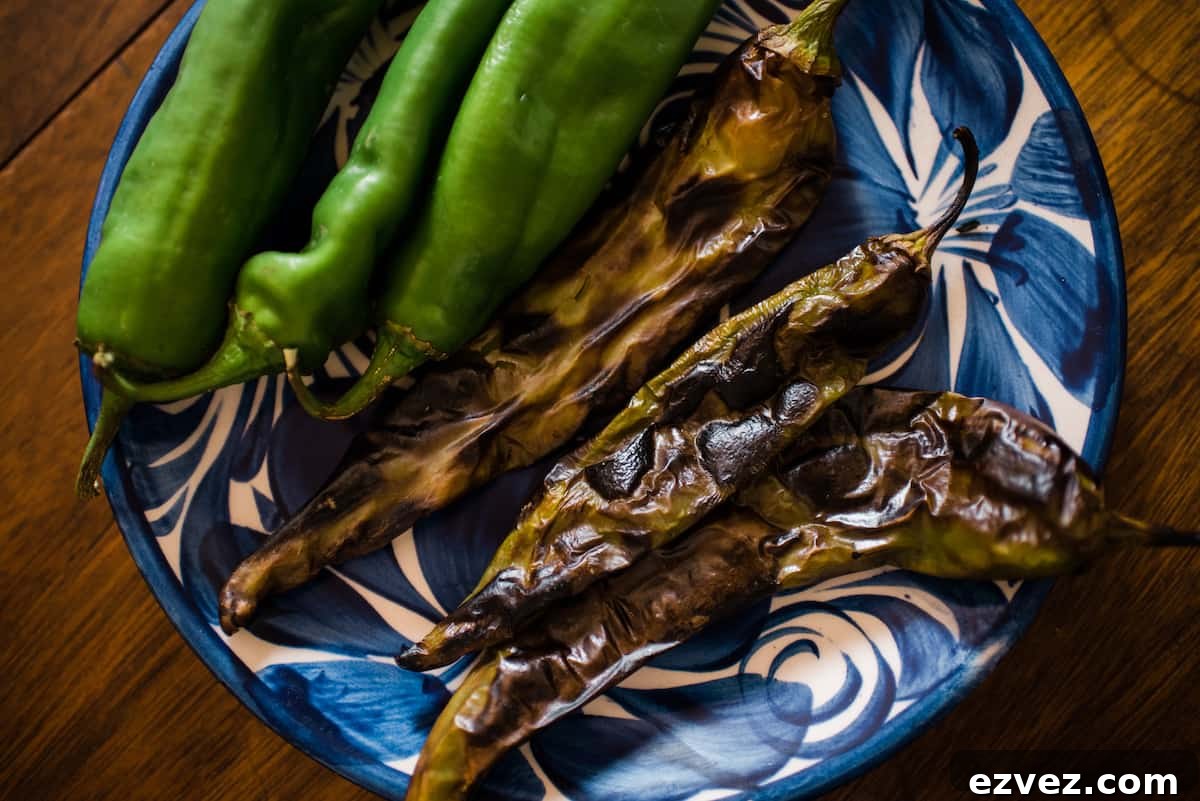 Colorado-Style Green Chile Pork Roast Recipe 3 fresh and roasted Chile peppers on a blue and white plate ready to make Colorado pork green chili stew.