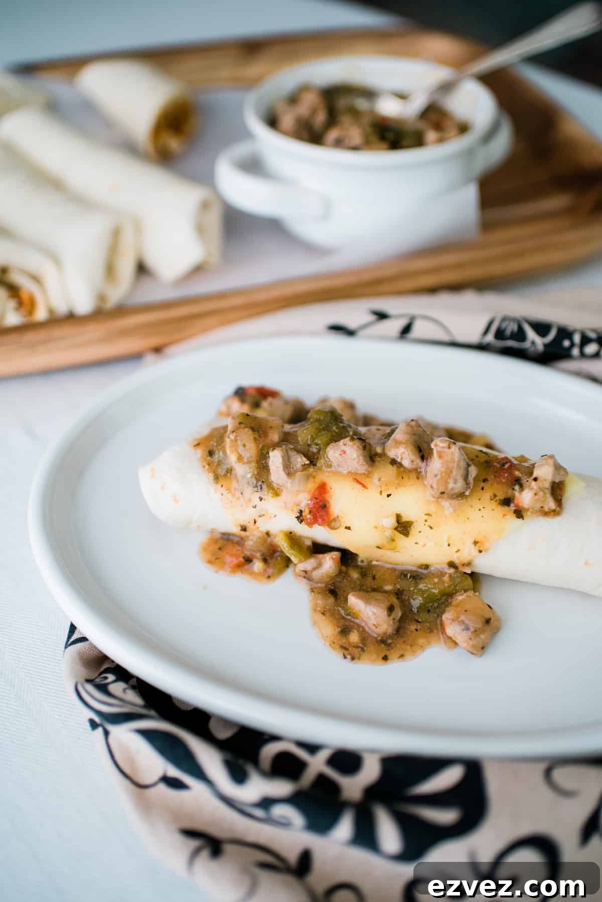 Colorado-Style Green Chile Pork Roast Recipe 8 a bowl of Colorado green chili pork stew in a white bowl with a breakfast burrito on a white plate.