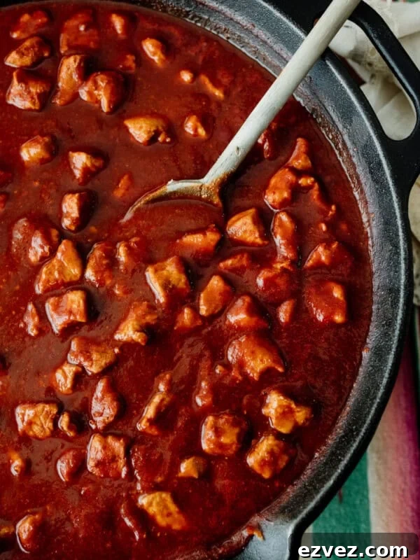 Colorado-Style Green Chile Pork Roast Recipe 10 Authentic Asado de Puerco in chile colorado sauce in a cast iron skillet, Mexican pork recipe by Yvette Marquez-Sharpnack of Muy Bueno.
