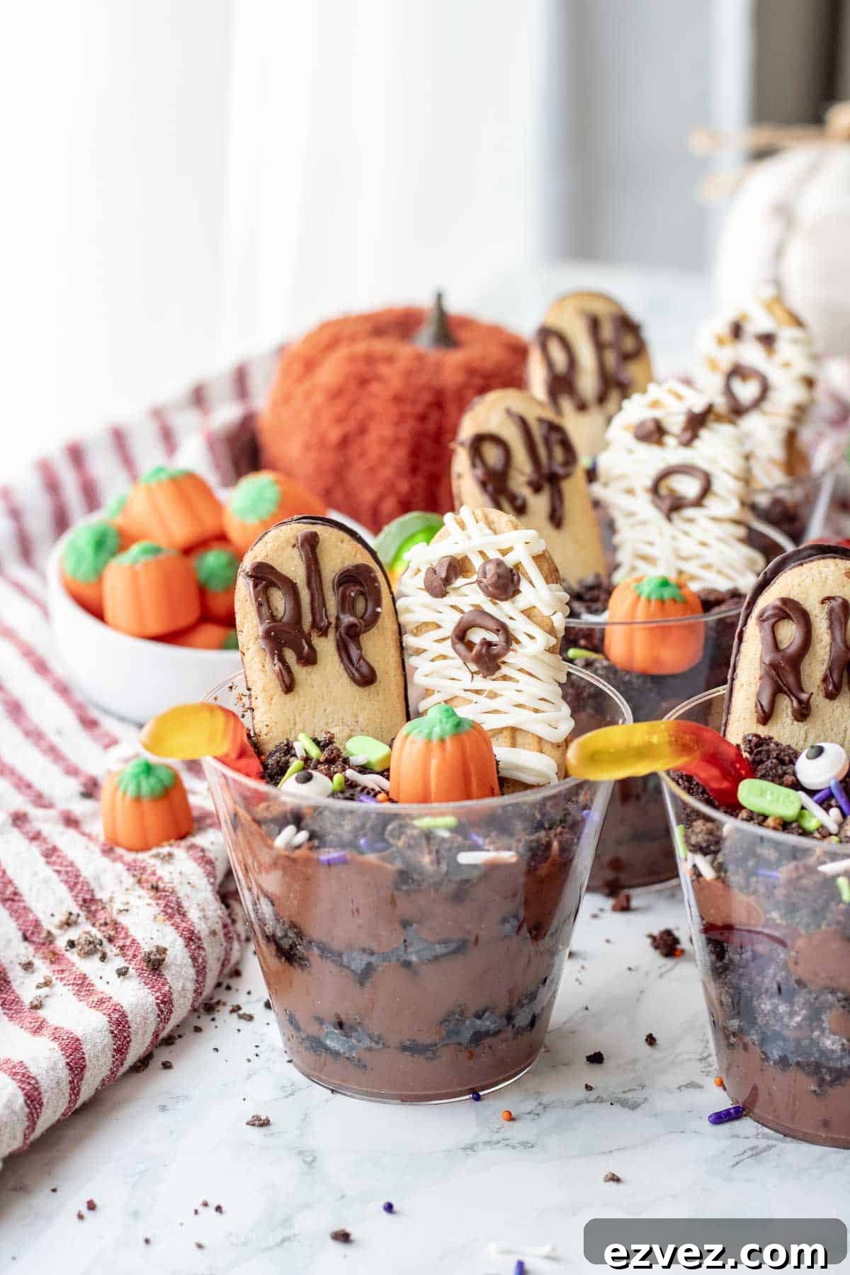Spooky Halloween Pudding Cups Recipe for Party Treats 11 Clear cup of pudding and Oreos with worms, headstone cookie, and mummy cookie.