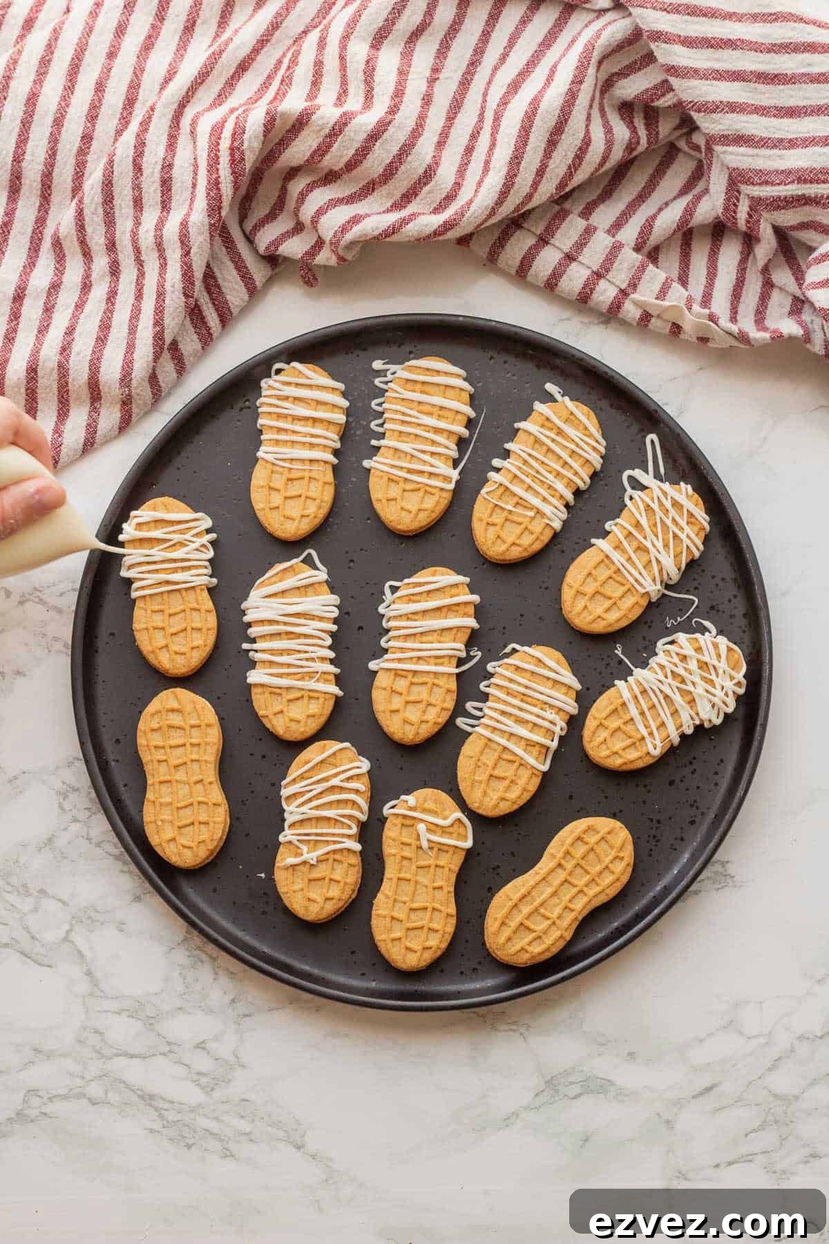 Spooky Halloween Pudding Cups Recipe for Party Treats 6 White chocolate being drizzled over nutter butter cookies on black plate.