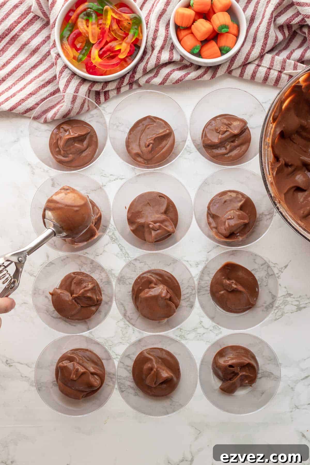 Spooky Halloween Pudding Cups Recipe for Party Treats 9 Chocolate pudding being scooped into plastic cups.