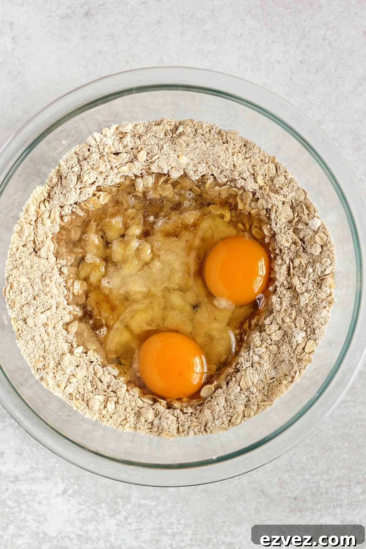 Dry ingredients for gluten-free banana muffins in a glass mixing bowl with wet ingredients added to the center of the dry ingredients.