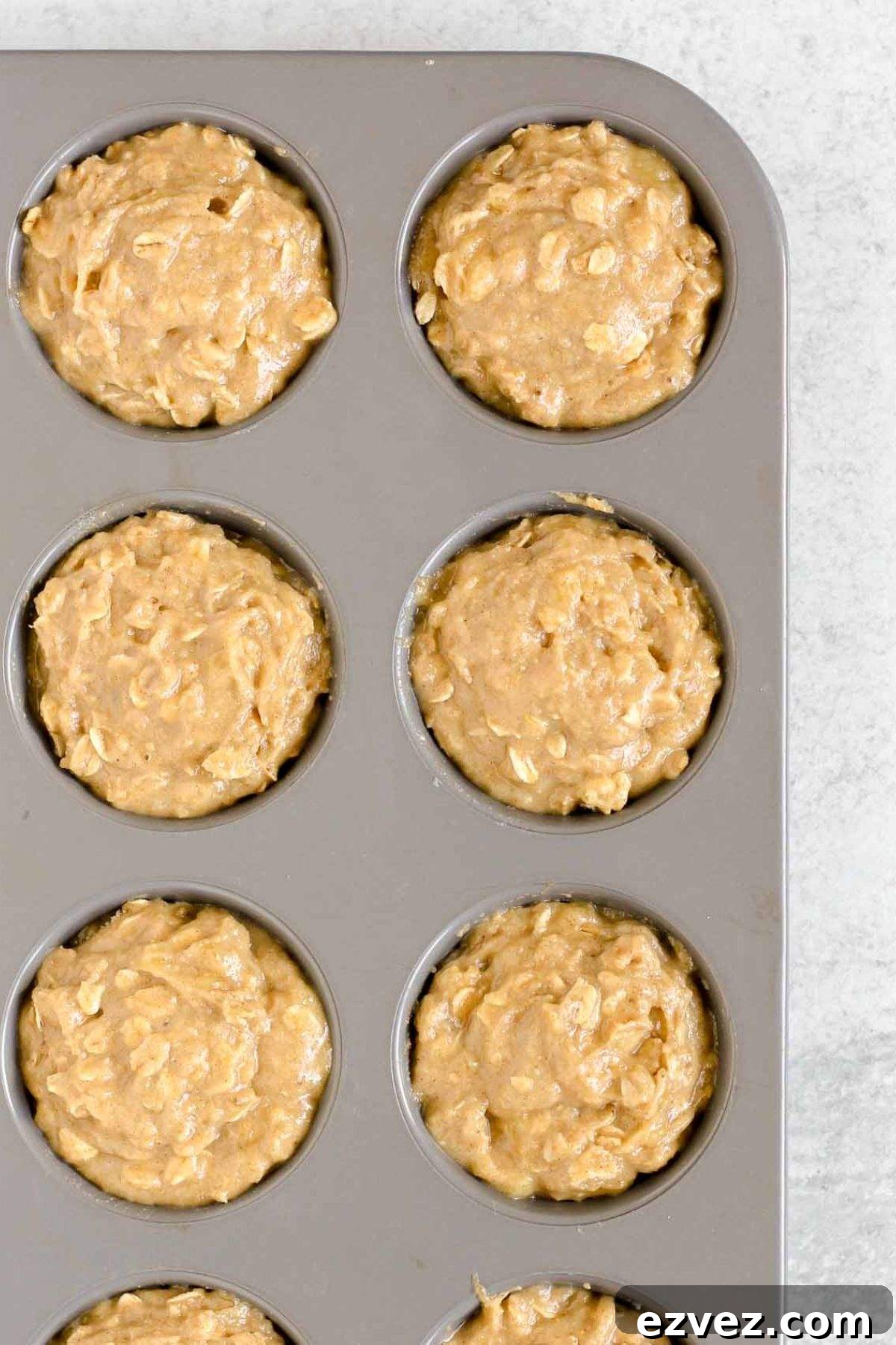 Banana muffin batter in a metal muffin pan.