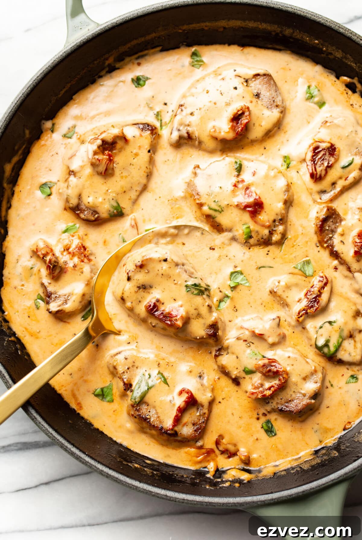 a skillet with marry me pork tenderloin and a serving spoon