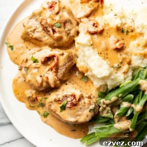 a plate with marry me pork tenderloin, mashed potatoes, and green beans