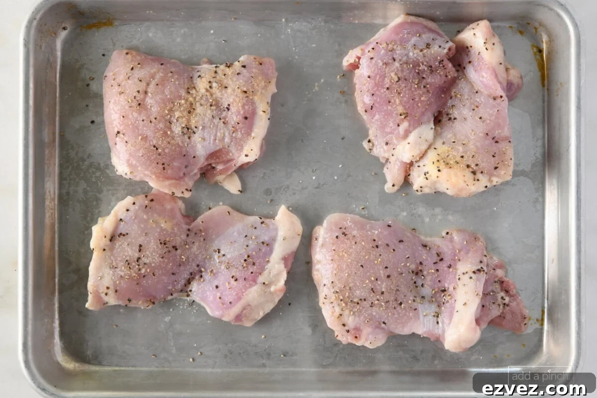 Marinated chicken thighs on a baking sheet.