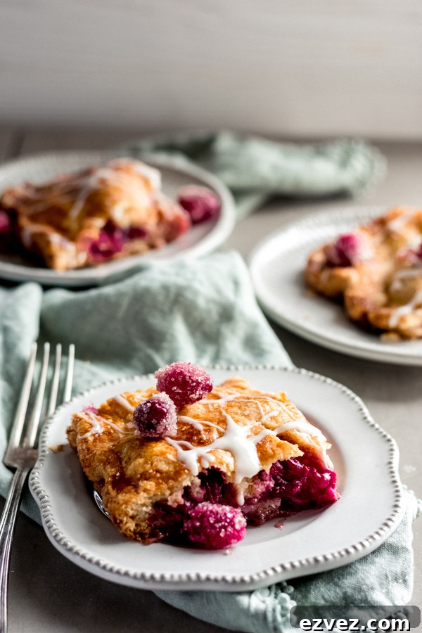 Squares of cranberry apple slab pie with maple glaze on plates.