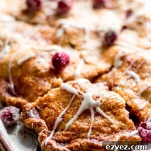 A close-up on the sliced cranberry apple pie drizzled with maple glaze.