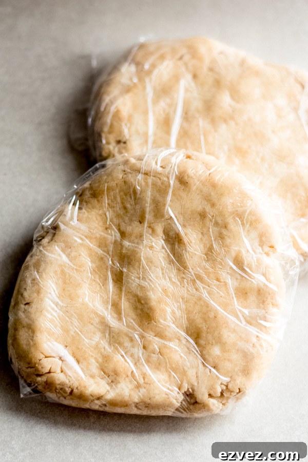 Two discs of pie dough, each wrapped in plastic wrap.