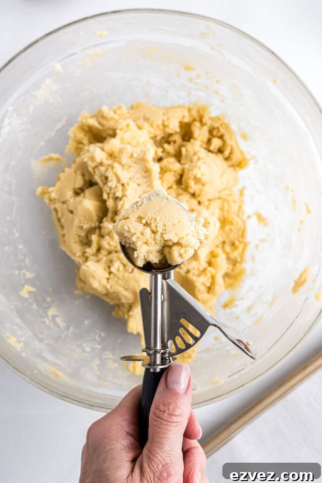 Close-up of cookie dough being scooped into balls for Candy Cane Kiss Cookies.