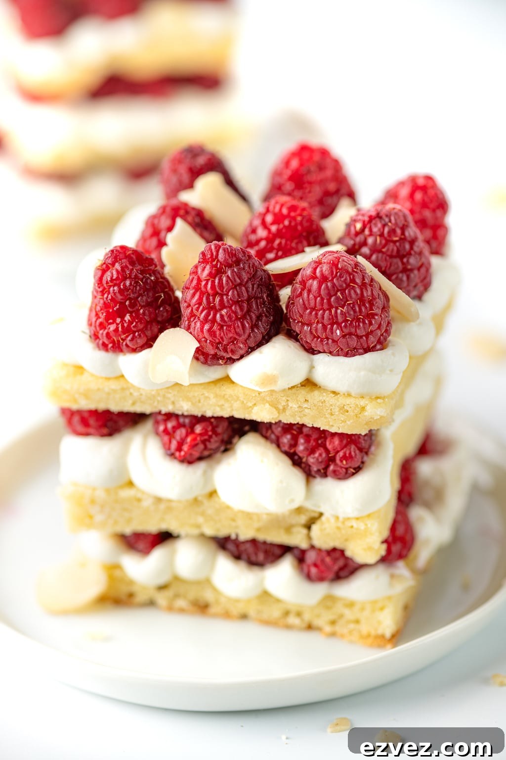 A 3-layer stack of keto shortcake, vanilla cream, and fresh raspberries.
