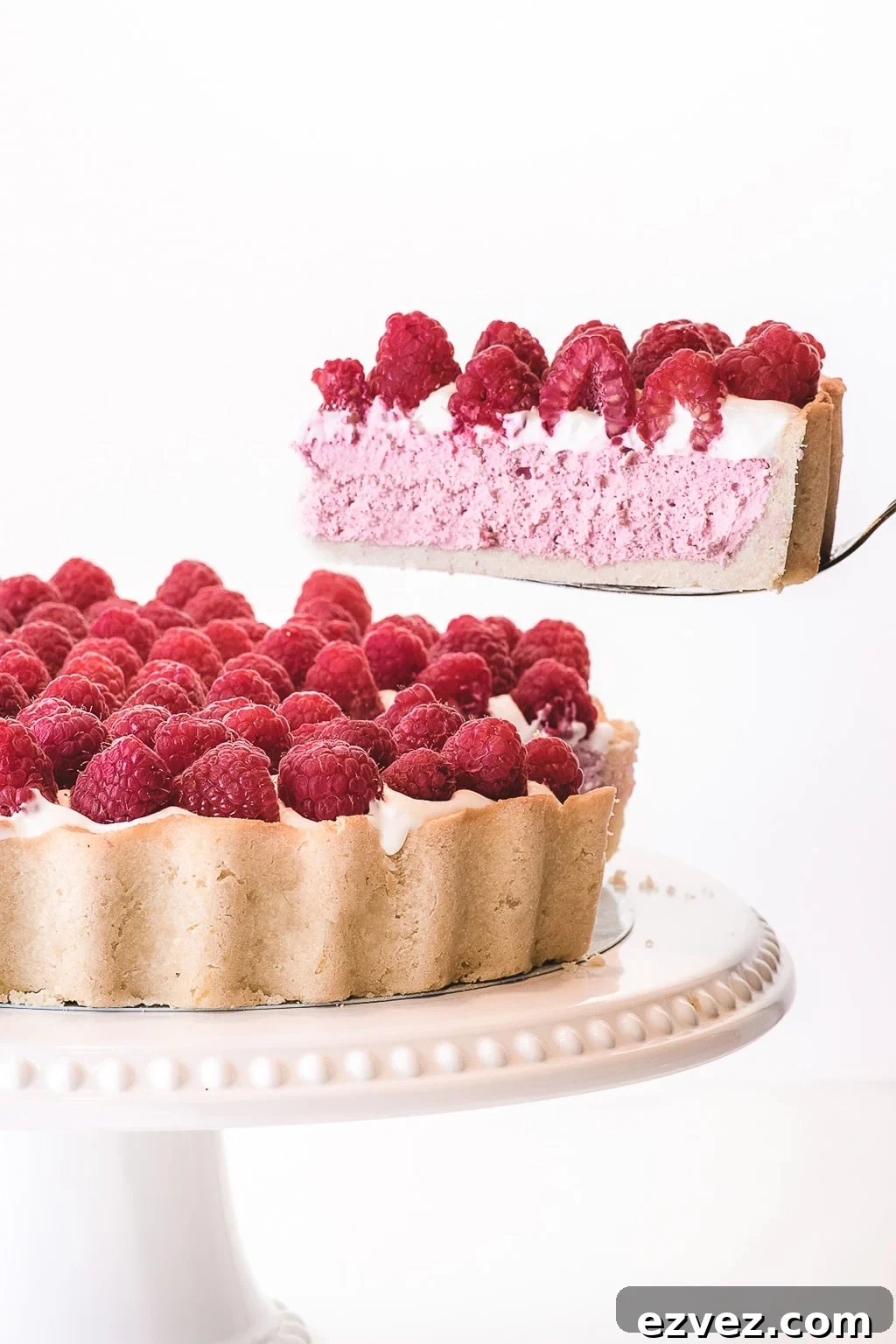 A slice of keto raspberry cheesecake being lifted from the whole, perfect for Valentine's day!