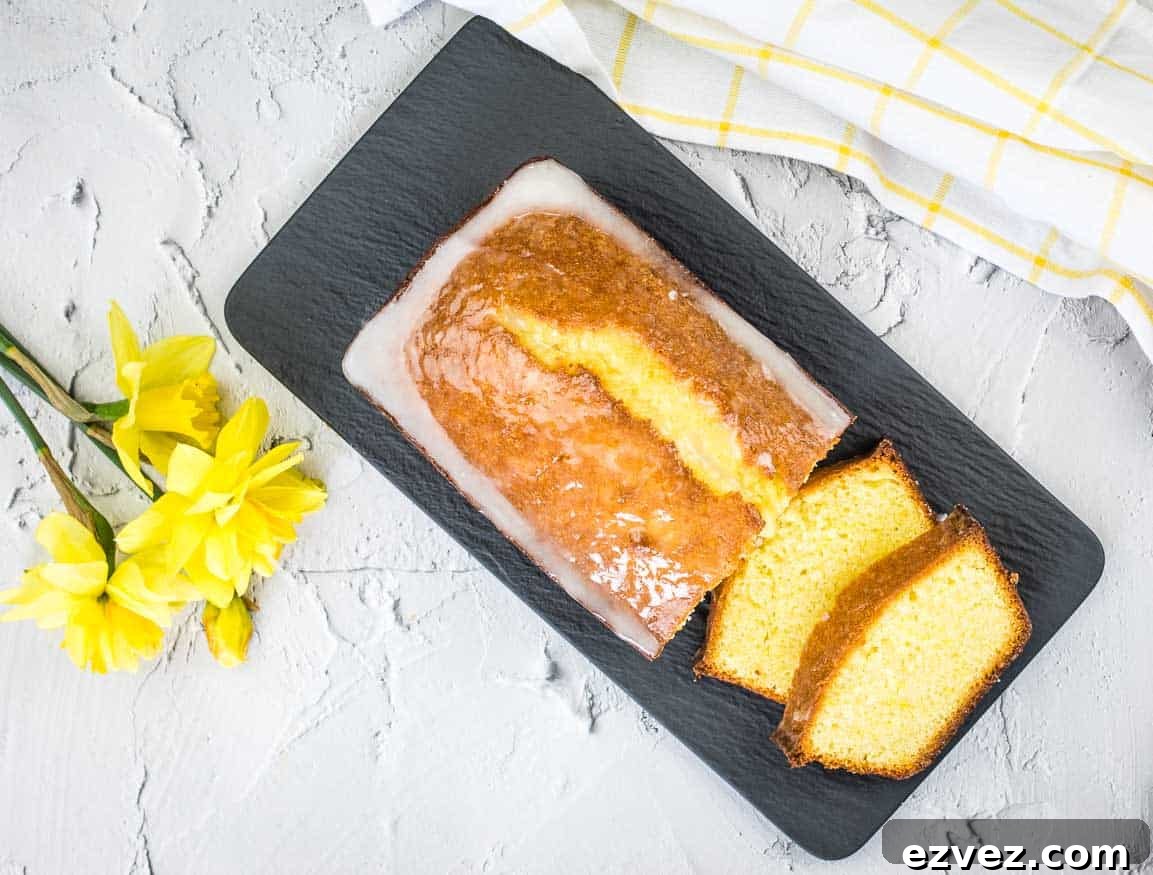 A slice of lemon pound loaf on a plate with daffodils.