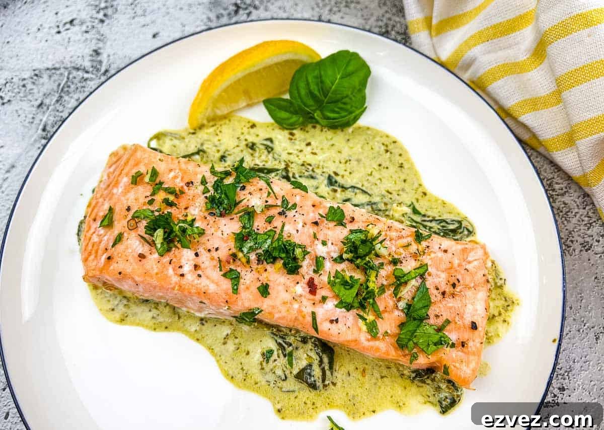Baked Pesto Salmon with spinach sauce on a white plate.